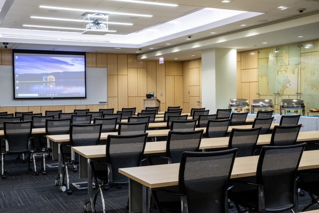 Conference Room 1AB at One Rotary Place. Photo of a large conference room with a podium, projector, and screen.