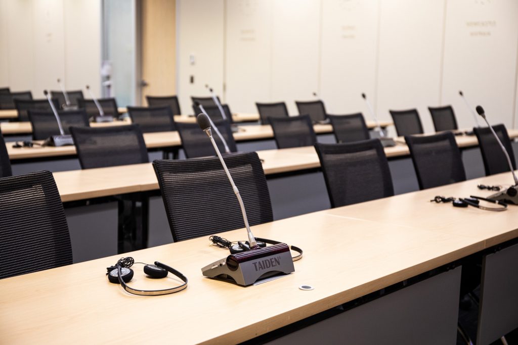 Conference Room 1A at One Rotary Place. Photo of a large conference room with chairs, microphones, and interpretation headsets.
