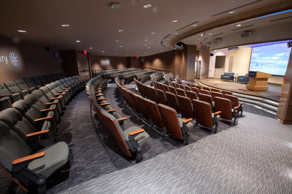 3rd Floor Auditorium at One Rotary Place. Photo of a large theater and stage featuring custom lighting and projections.